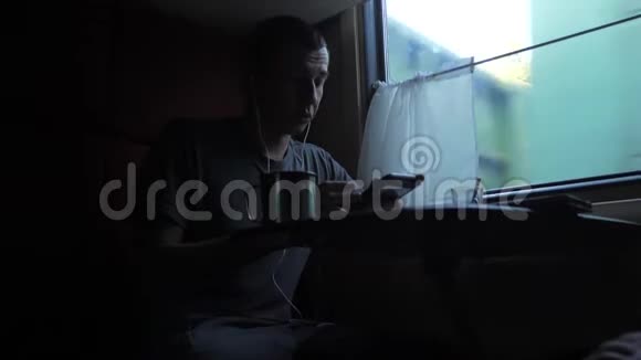 男子剪影旅行坐在火车车厢上手里拿着智能手机铁路喝着咖啡和茶慢慢慢慢视频的预览图