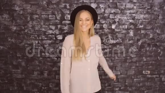 戴着黑色帽子和灰色衬衫的模特在砖墙背景上摆姿势视频的预览图