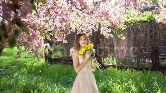 英俊的年轻女子在开花的花园里捧着一束郁金香视频的预览图
