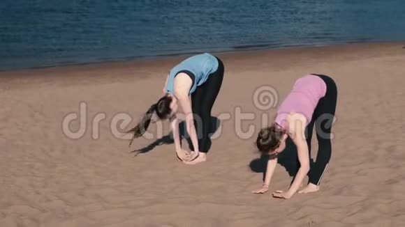 两个女人在城市河边的海滩上做瑜伽美丽的景色视频的预览图