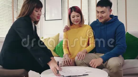 性格开朗的年轻人和妻子一起坐在办公桌前签署一些文件购买新房房产视频的预览图