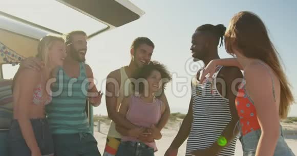 年轻的成年朋友站在沙滩4k的露营车旁视频的预览图