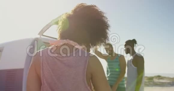 年轻的成年朋友站在沙滩4k的露营车旁视频的预览图