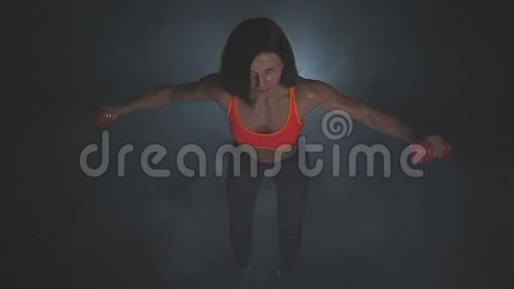 漂亮的健身女人举起哑铃运动女孩展示她训练有素的身体发达的肌肉视频的预览图
