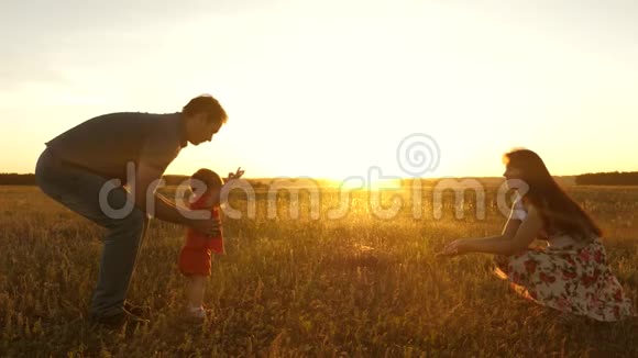 爸爸和妈妈在阳光下和一个小女儿在野外玩耍小女儿在阳光下从爸爸变成妈妈母亲视频的预览图