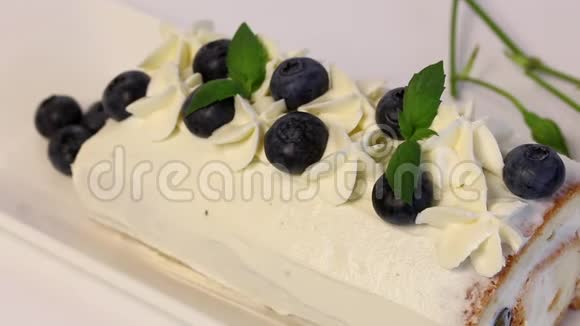涂上奶油的海绵蛋糕用干蓝莓和新鲜薄荷叶装饰视频的预览图
