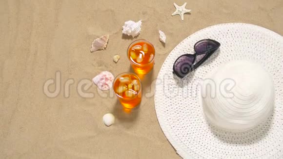 沙滩沙上的鸡尾酒太阳帽和太阳镜视频的预览图