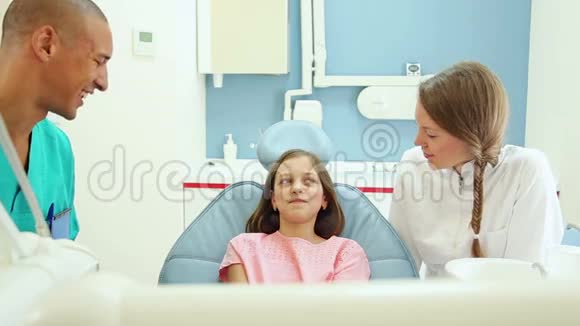 友好的牙医和她的助手和可爱的小女孩聊天视频的预览图
