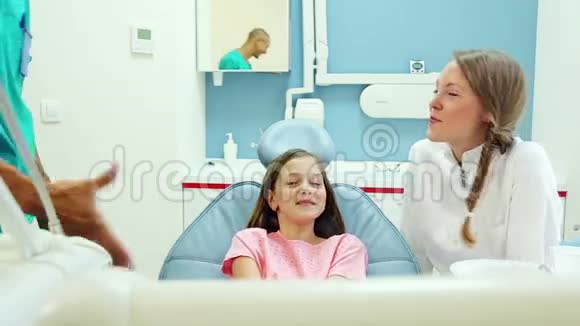 友好的牙医和她的助手和可爱的小女孩聊天视频的预览图