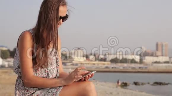 海边的年轻女子带着手机视频的预览图