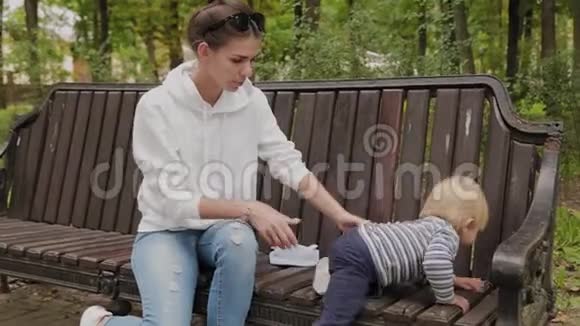 快乐的母亲和她的儿子在公园的长凳上视频的预览图