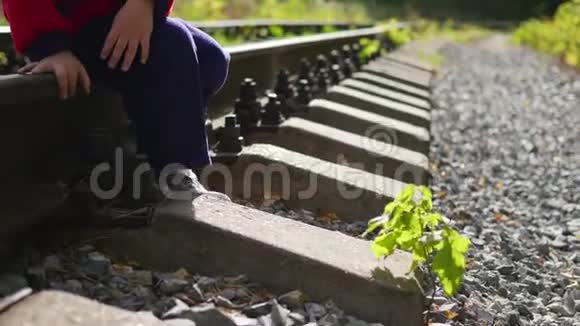 一个孤独的男孩坐在铁轨上危险的游戏和娱乐视频的预览图