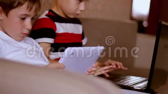 两个男孩在家玩平板电脑和笔记本电脑视频的预览图