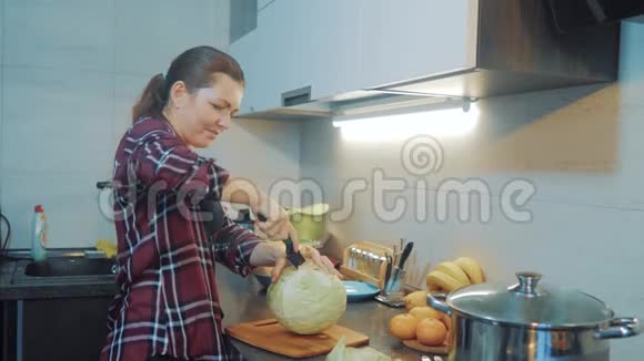 厨房里的女人准备一顿饭的概念厨房里的女孩用刀切卷心菜烹饪素食视频的预览图
