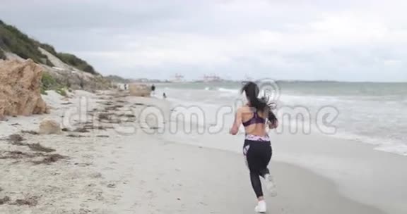 年轻健康的运动女人在海滩上慢跑超级慢动作稳定器射击视频的预览图