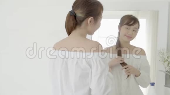 美丽的肖像年轻的亚洲女人微笑着看着镜子检查皮肤护理白种人在卧室健康视频的预览图