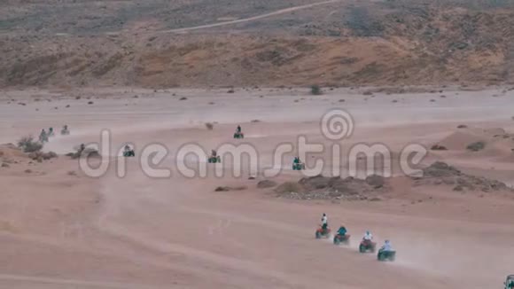 在埃及的沙漠中骑四方自行车小组以山脉为背景驾驶ATV视频的预览图