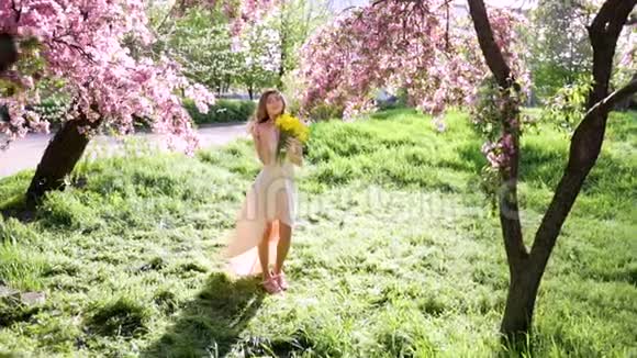 英俊的年轻女子在开花的花园里捧着一束郁金香视频的预览图