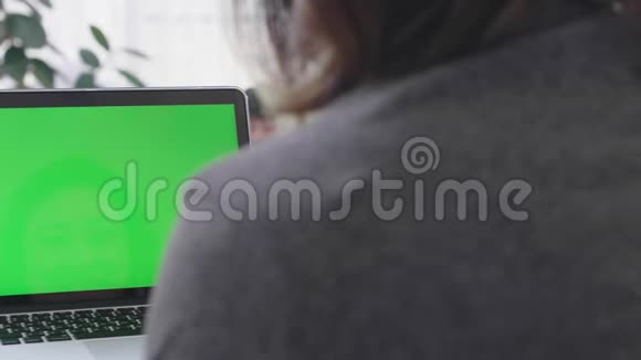 过肩射的亚洲女子看着绿屏视频的预览图