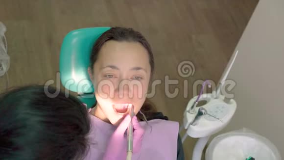 儿科牙医在牙科诊所的牙医椅上检查一个小男孩的牙齿带着牙医的孩子视频的预览图