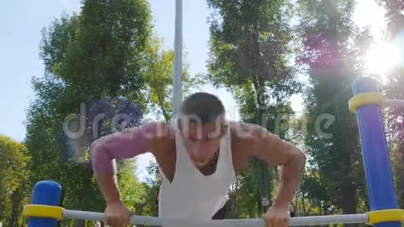 在城市公园的运动场上做俯卧撑的运动员强壮的年轻肌肉男夏季户外训练视频的预览图