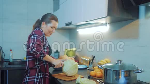 厨房里的女人准备一顿饭的概念厨房里的女孩用刀切卷心菜烹饪素食食品视频的预览图