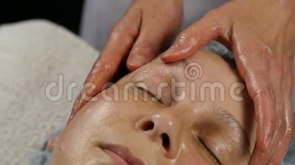 在水疗中心接受头部按摩的女人做面部按摩的女医生慢动作视频的预览图