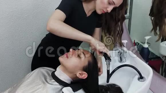 漂亮的年轻女孩在理发店洗头视频的预览图