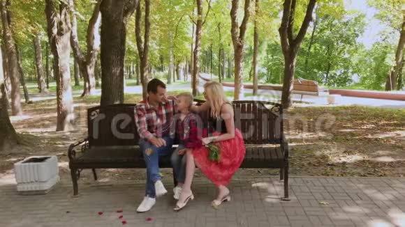 美丽的一家人坐在公园的长凳上聊天视频的预览图