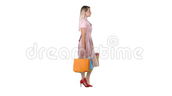 快乐的漂亮女孩拿着白色背景上的购物袋走路视频的预览图