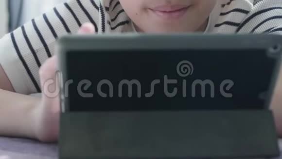 接近亚洲男孩在平板电脑上玩视频的预览图