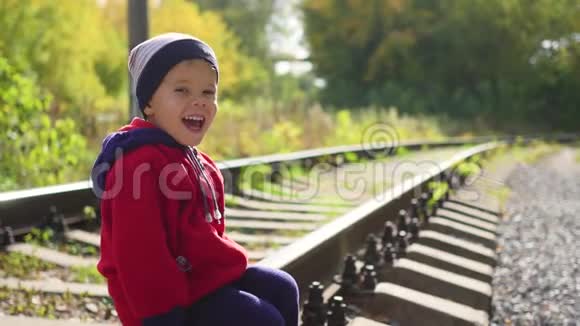 一个孤独的男孩坐在铁轨上危险的游戏和娱乐视频的预览图