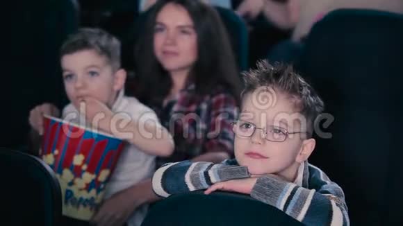 那个戴眼镜的男孩正在电影院看电影视频的预览图