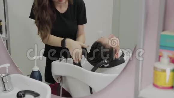 漂亮的年轻女孩在理发店洗头视频的预览图