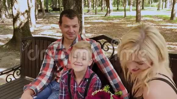 美丽的一家人坐在公园的长凳上聊天视频的预览图