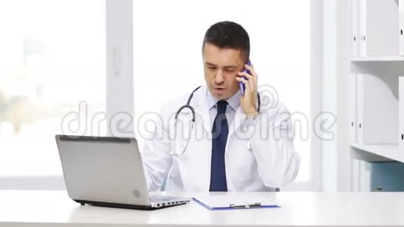 带手提电脑的医生打电话给智能手机视频的预览图