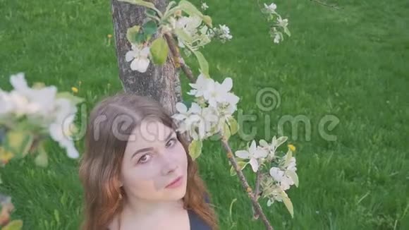 年轻快乐的女人走在苹果园里的春天花白了一个漂亮女孩的肖像视频的预览图