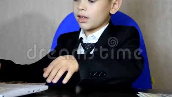 年轻的商人用笔记本电脑现代办公室时尚儿童帅哥坐在扶手椅的桌子旁数着钱视频的预览图