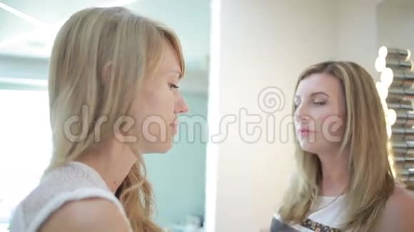 美容院的女孩化妆师和理发师为一个女人工作视频的预览图
