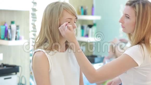 美容院的女孩化妆师和理发师为一个女人工作视频的预览图