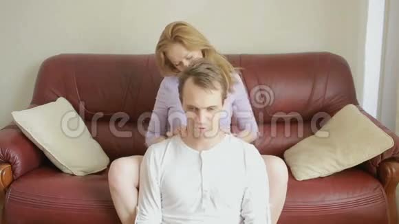 年轻夫妇在客厅的沙发上放松轻轻地拥抱和交谈视频的预览图
