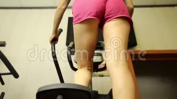 年轻女子参加体育运动在健身房健身女孩在模拟器上做运动视频的预览图