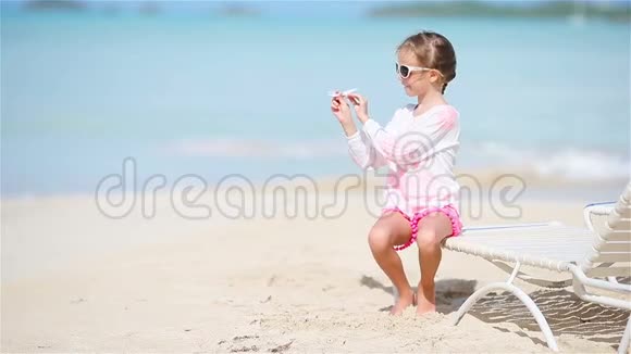 快乐的小女孩手里拿着玩具飞机在白色沙滩上小孩在海滩上玩玩具视频的预览图