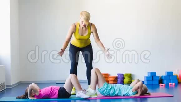 在健身课上做体操的女生和指导员或妈妈视频的预览图
