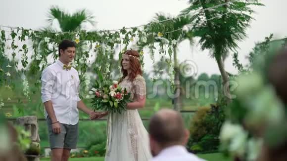 新娘和新郎在婚礼上晚上的热带花园可爱的新婚夫妇视频的预览图