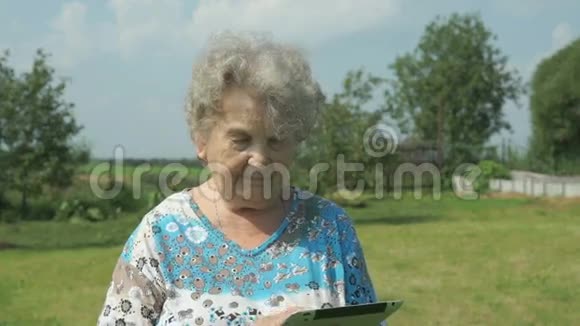 80多岁的老太太在户外拿着数码平板电脑视频的预览图
