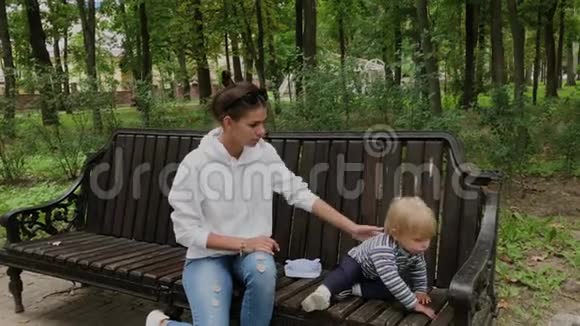 快乐的母亲和她的儿子在公园的长凳上视频的预览图