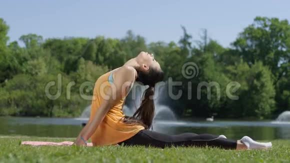 年轻女性在夏天早上在公园里做运动伸展运动和瑜伽视频的预览图