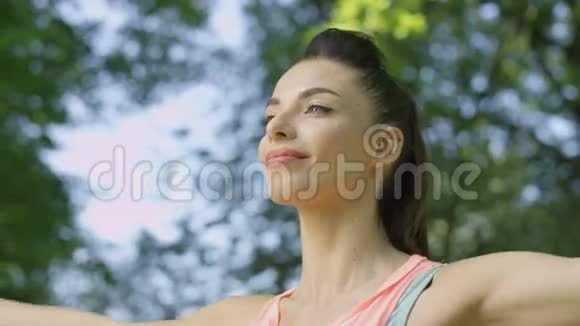 年轻女性在夏天早上在公园里做运动伸展运动和瑜伽视频的预览图