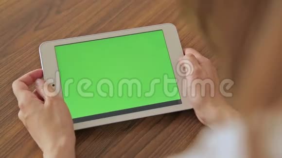 漂亮的女人手拿着绿色屏幕显示器的平板电脑视频的预览图